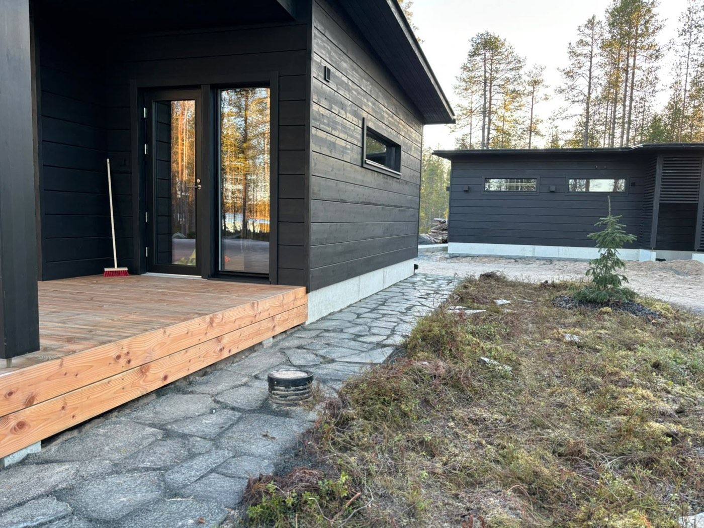 Luonnonkivipolku mustan mökin puuterassille