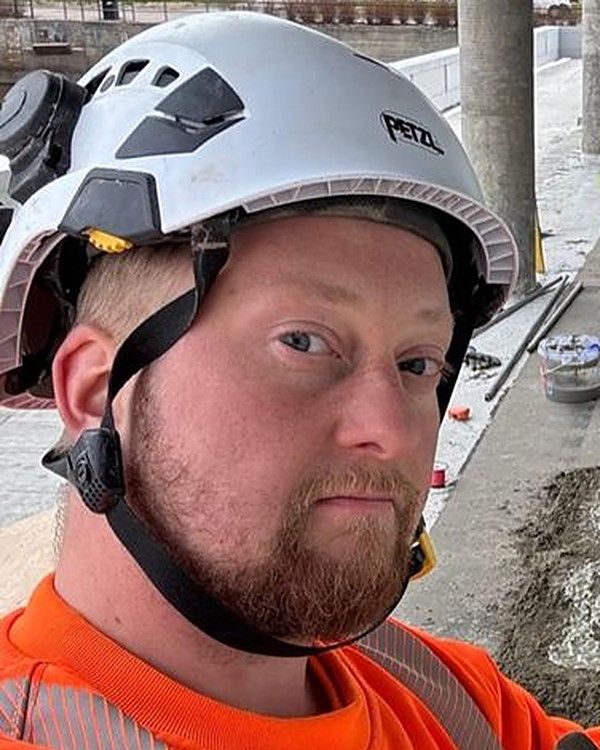 Toinen veljeksistä työmaalla kypärä päässä ja oranssi huomiotakki yllä